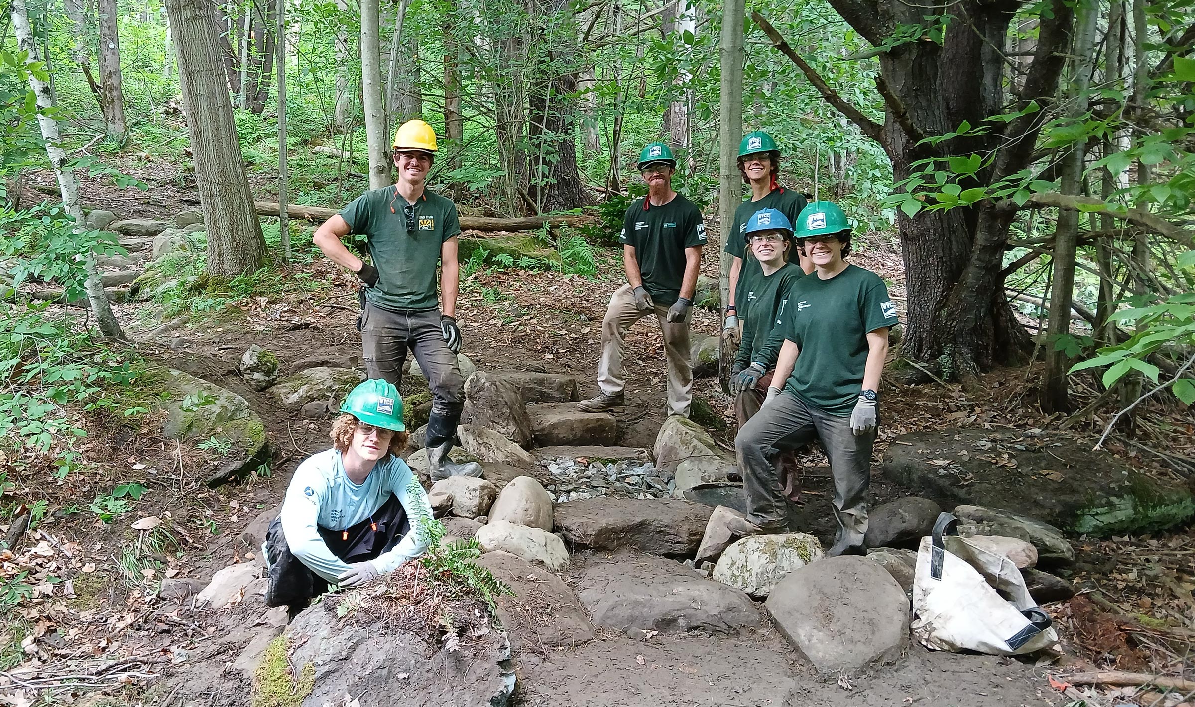 A Conservation trail crew stands next to a newly-improved, rock-reinforced pathway.